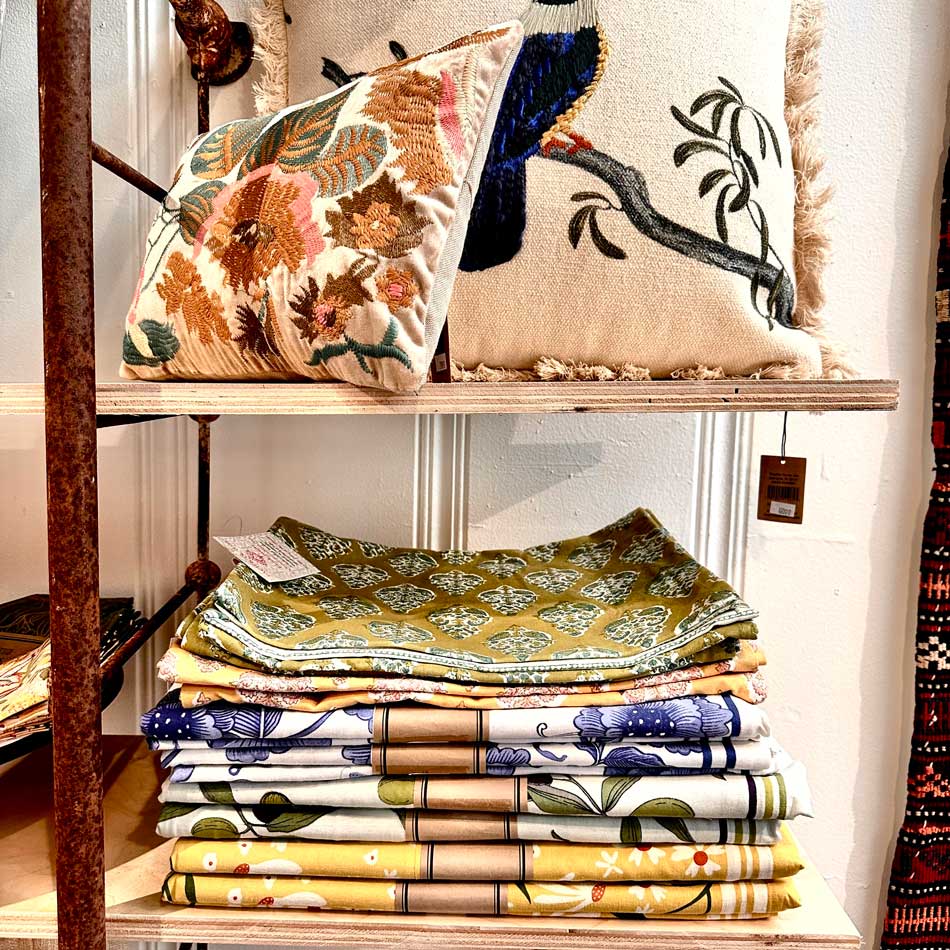 Embroidered pillows and linens on a shelf